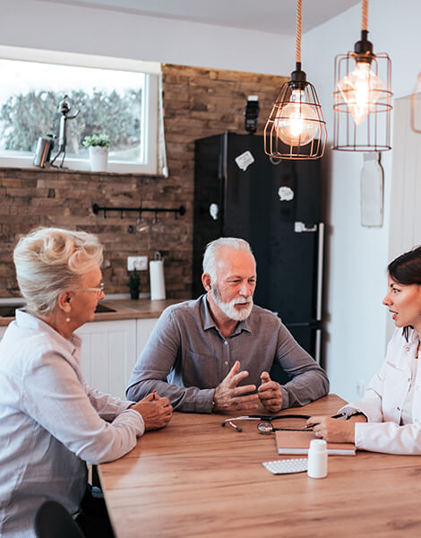 An informal consultation between an older couple and a doctor discussing health care requirements and funding options